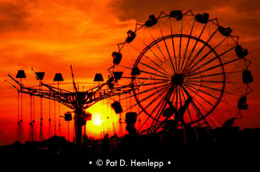 The sun sets behind carnival rides in a Kmart parking lot in Russell, Ky., June 1977.